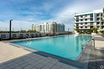 A large swimming pool with a tiled edge and a metal railing on our rooftop patio at Hollywood Heights on the Boulevard Luxury Apartments in Hollywood, FL